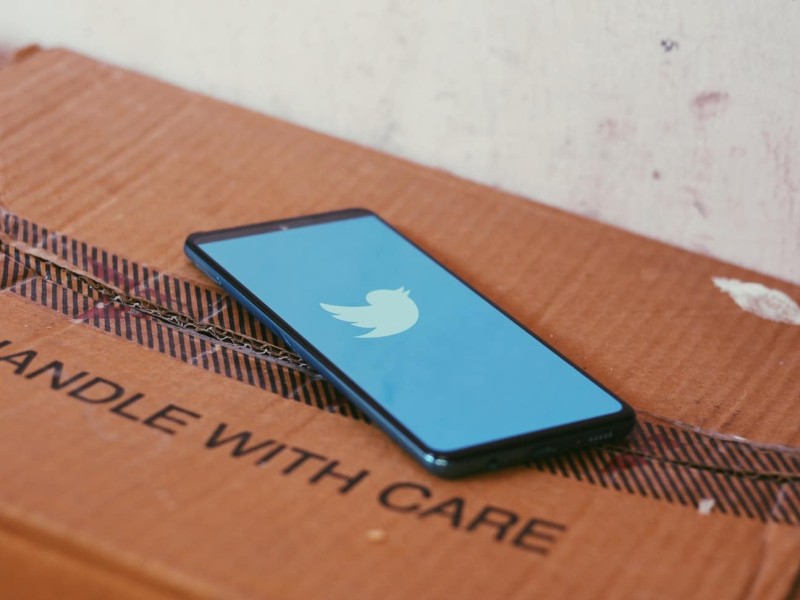 A phone on a box with the Twitter loading screen. The box reads Handle With Care.