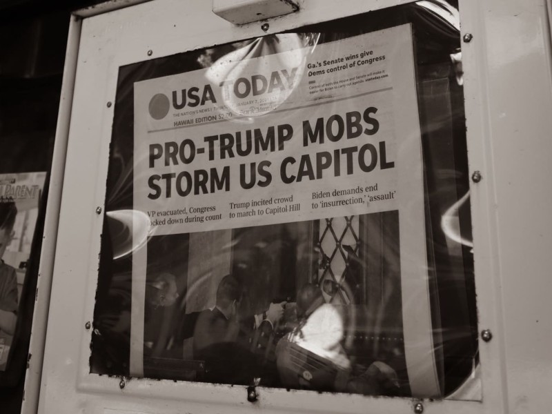 USA Today cover reads “Pro-Trump mobs storm US Capitol” in newspaper rack.