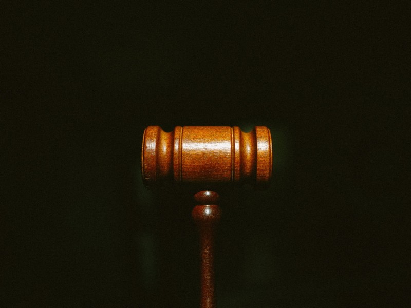 Alt: A closeup image of a wooden gavel against a black background.
