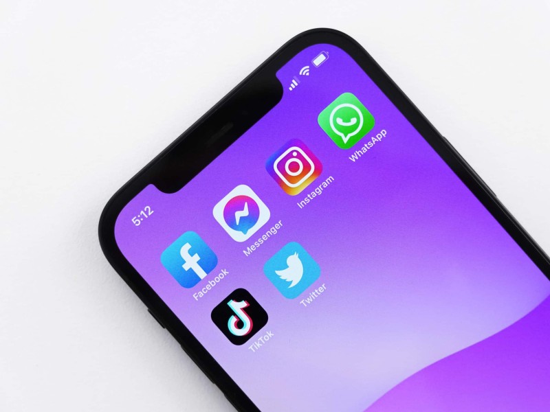 Close up photo of the upper half of an iPhone. The apps on the screen are Facebook, Messenger, Instagram, WhatsApp, Tiktok, and Twitter.
