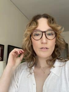 The author wears glasses and a white button-up, looking straight into the camera.