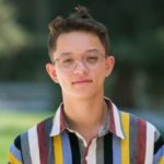 Headshot of Brandon Pho. He wears a striped button up shirt and is standing outside.