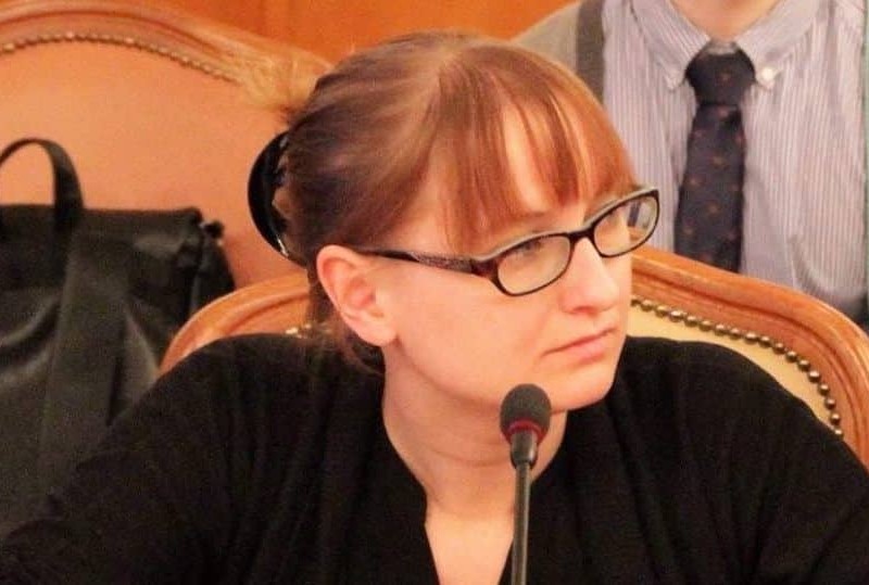 Photo of Samantha Sunne. She is speaking into a microphone, and her head is turned to the right side.