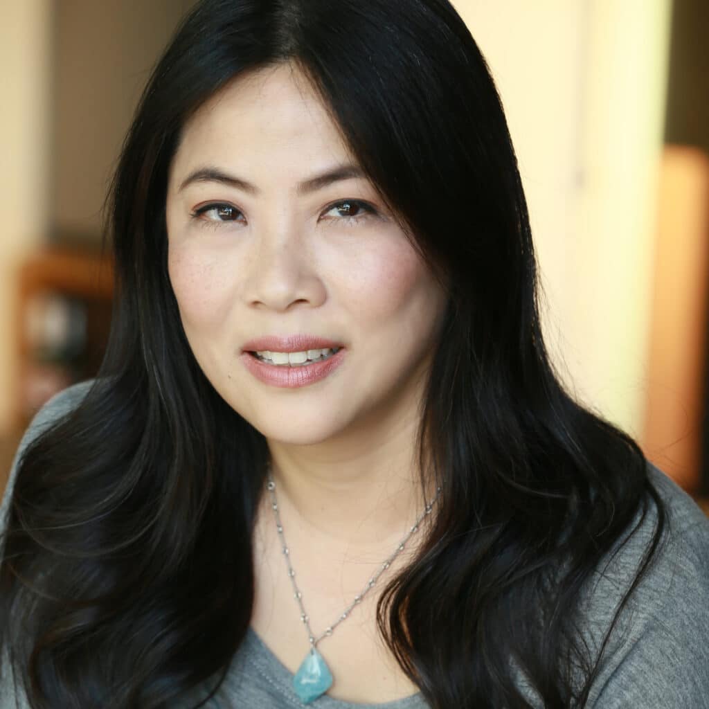 Headshot of Karen Yin. She has long black hair that’s slightly wavy, a silver chain necklace and a gray top. Yin has a neutral expression on their face.