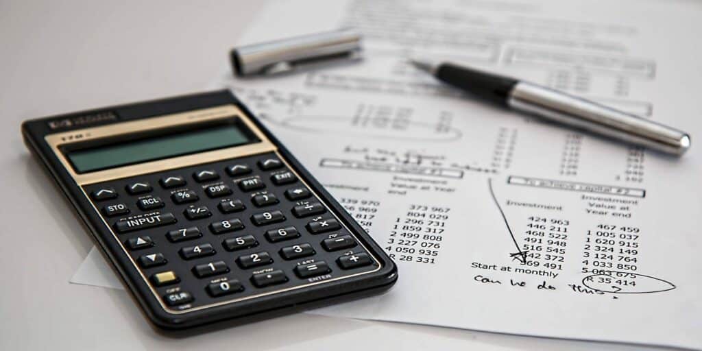A stock photo of a calculator on top of a typed-out sheet of freelance expenses and bills.