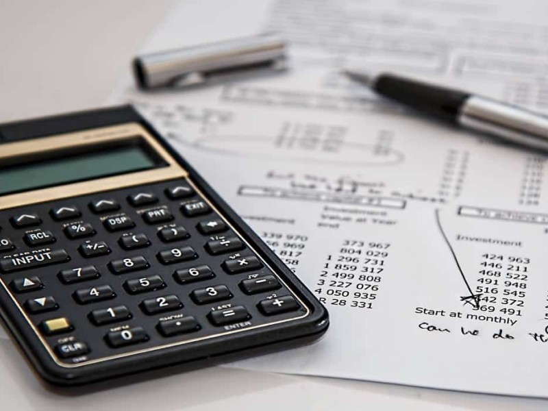 A stock photo of a calculator on top of a typed-out sheet of freelance expenses and bills.