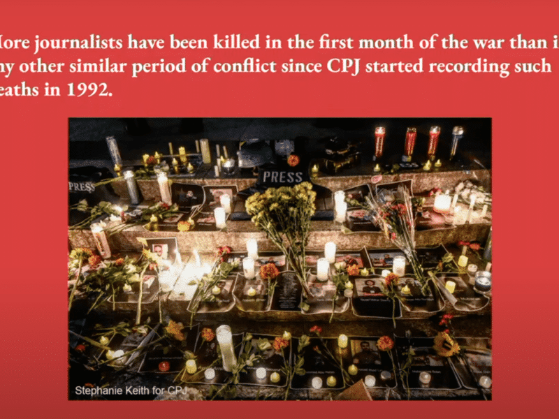 A red slide from a presentation that reads "More journalists have been killed in the first month of the war than in any other similar period of conflict since CPJ started recording such deaths in 1992." A photo of graves for journalists with flowers, candles, and their photos is under the text.