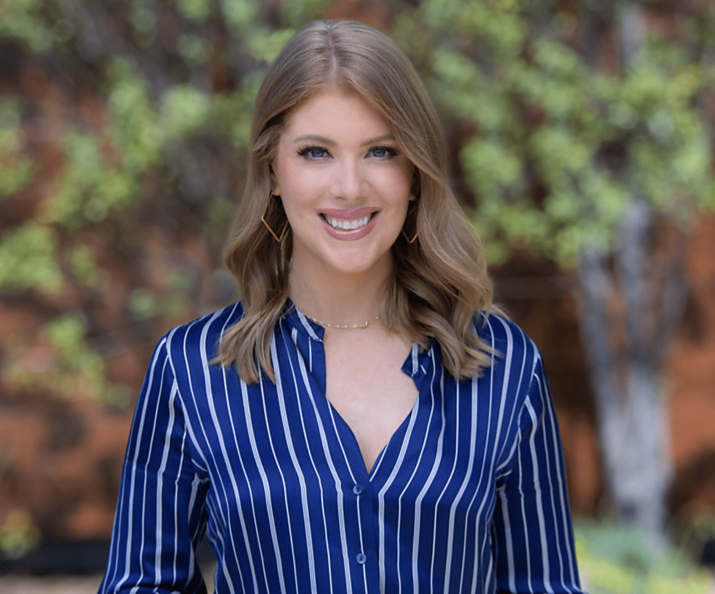 Headshot of Kate Cagle, a white woman with curled blonde hair and blue eyes, wearing a blue and white striped button-up.