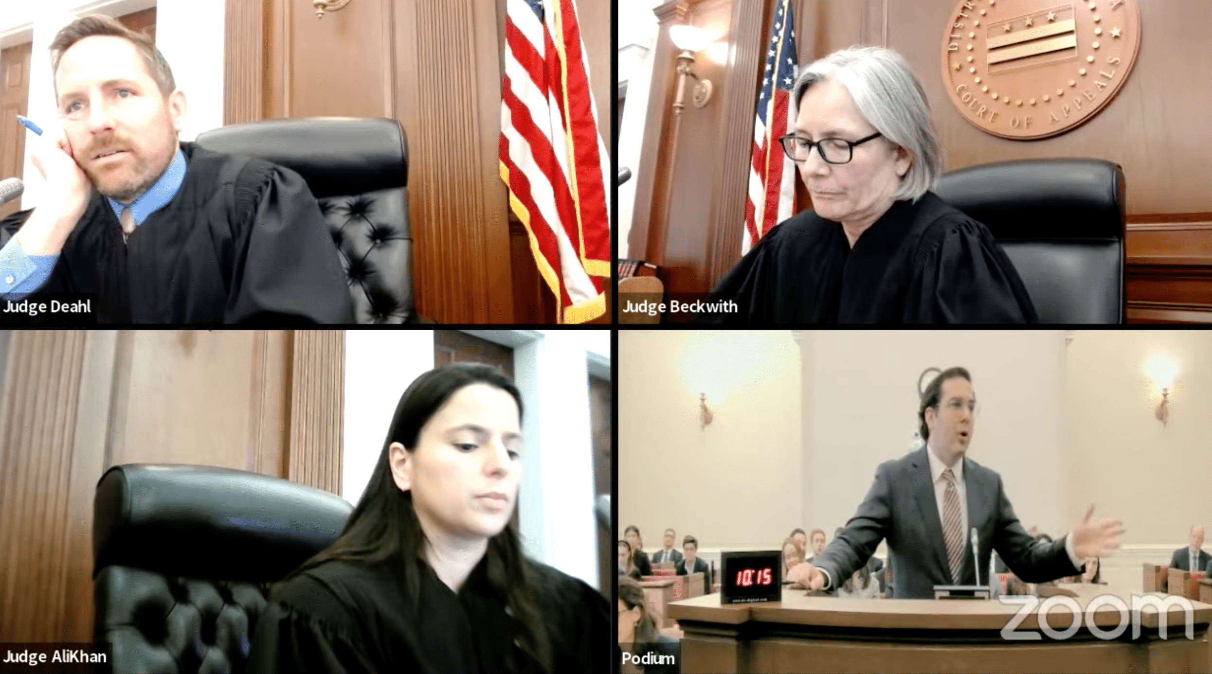A Zoom screenshot of a hearing before the D.C. Court of Appeals. Three judges are in three of the four Zoom boxes: Judge Deahl, a middle-aged white man, at top left; Judge Beckwith, an older white woman, at top right; Judge AliKhan, a middle-aged Pakistani woman at bottom left. In the Zoom box at bottom right is Yaakov Roth, at the podium.