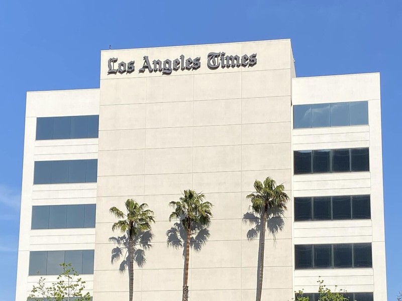 The front of the Los Angeles Times building, a white-facade high-rise showing the Los Angeles Times signage.