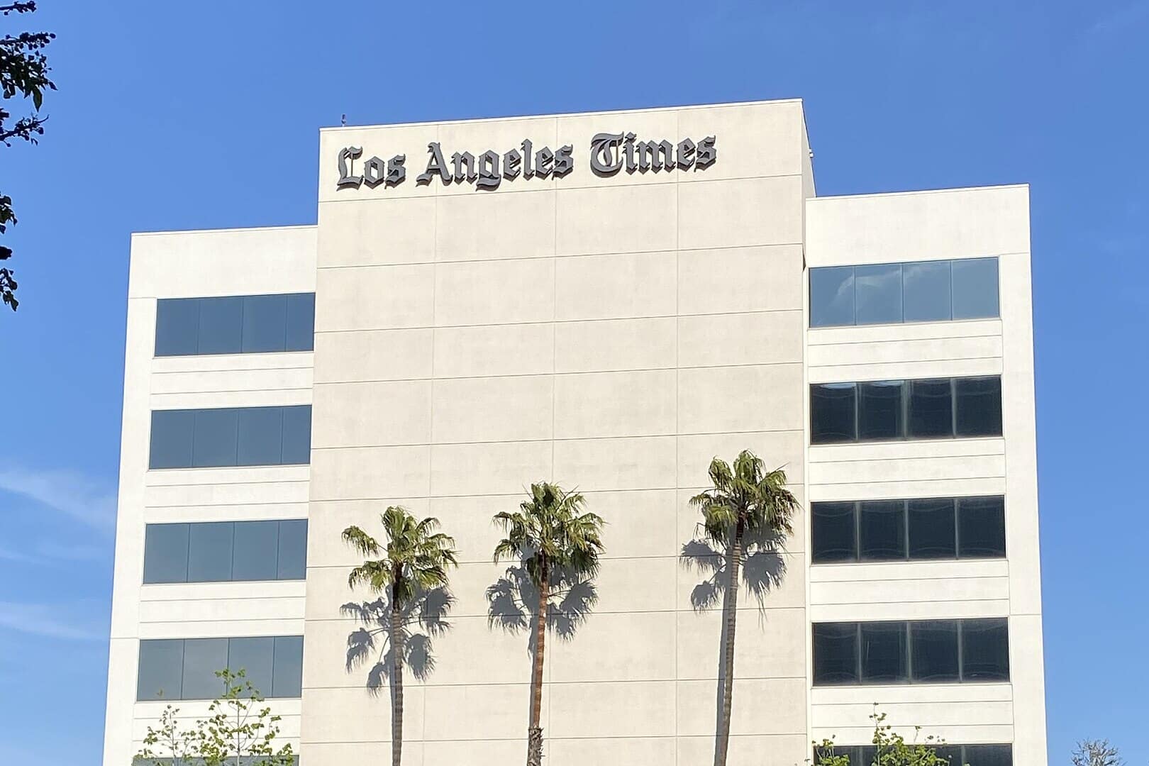 The front of the Los Angeles Times building, a white-facade high-rise showing the Los Angeles Times signage.