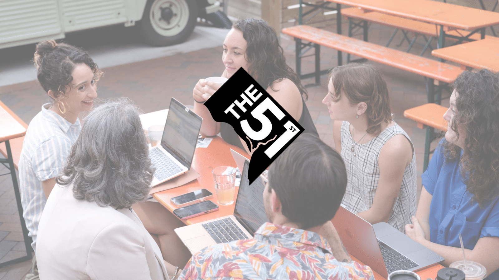 The logo of The 51st — the shape of Washington, D.C. colored black with "The 51st" laid over it, with the Potomac River running halfway between the 5 and 1 — sits on top of a slightly faded photo of the six co-founders of The 51st. They are sitting outside around a table. From top left clockwise: Natalie Delgadillo, Abigail Higgins, Colleen Grablick, Maddie Poore, Eric Falquero, and Teresa Frontado.