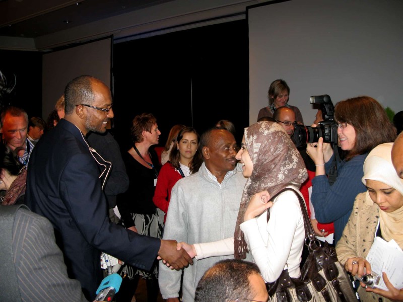 Attendees of the Global International Journalism Conference 2008 congregate. Front and center is Al Jazeera journalist Sami Al-Hajj, a Sudanese man, shaking hands with a hijabi journalist.