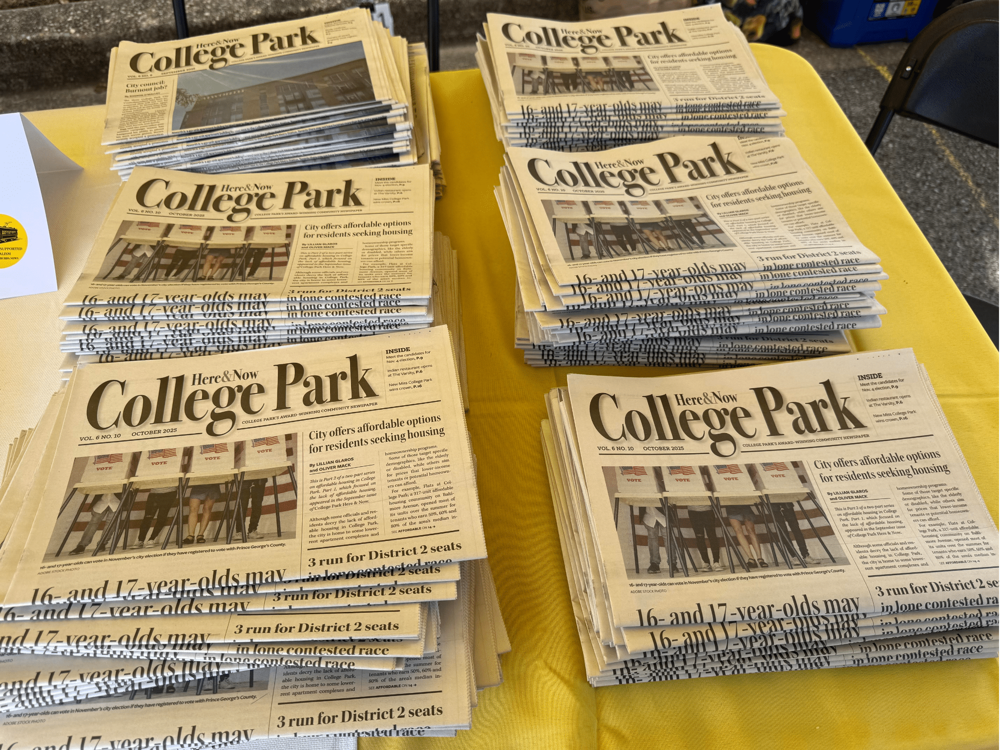 A table piled with College Park Here & Now papers.