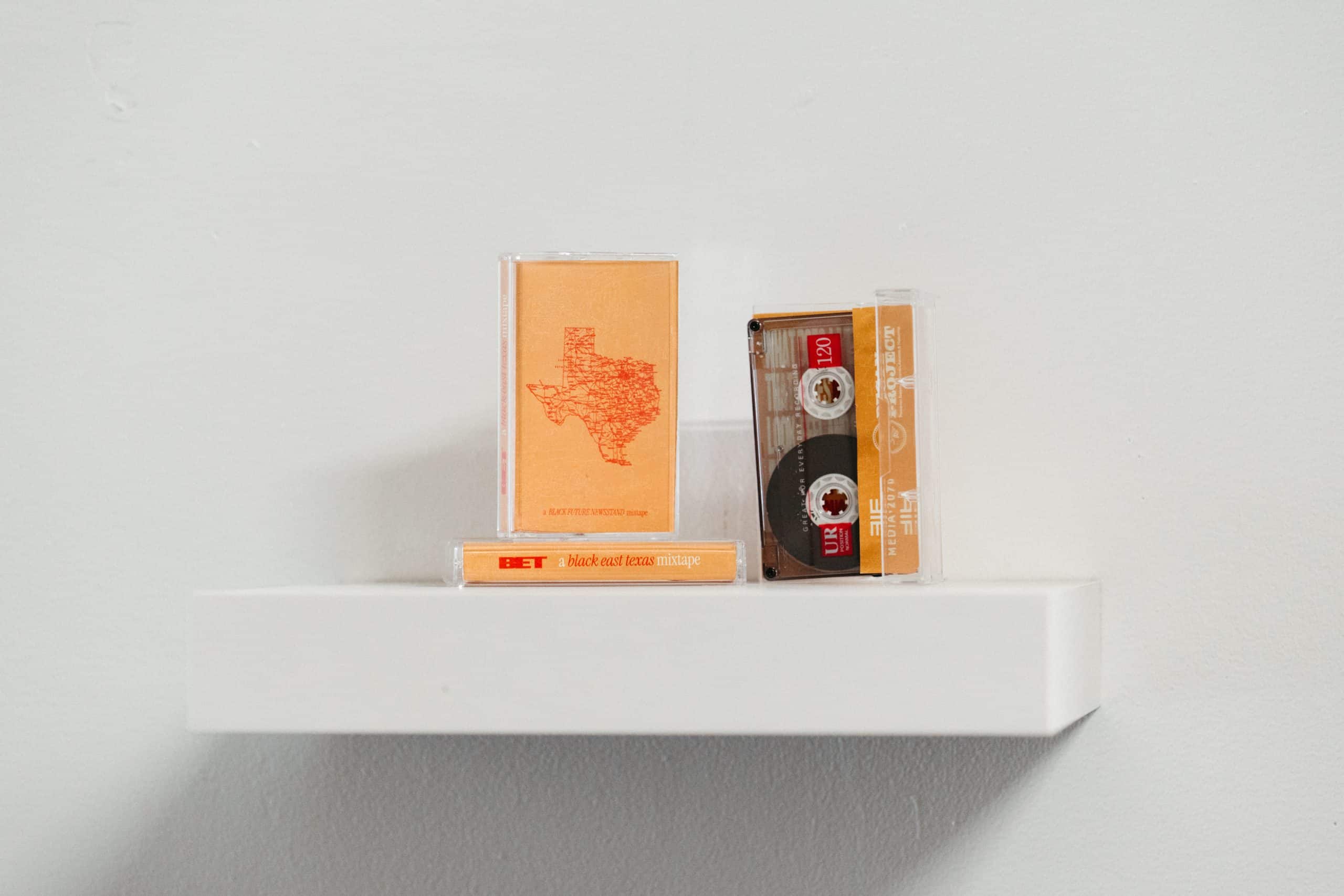 Three mixtape cassettes presented at the latest Black Futures Newsstand, with a yellow cover that depicts Texas. One cassette is on the side and shows the label: BET, a black east texas mixtape