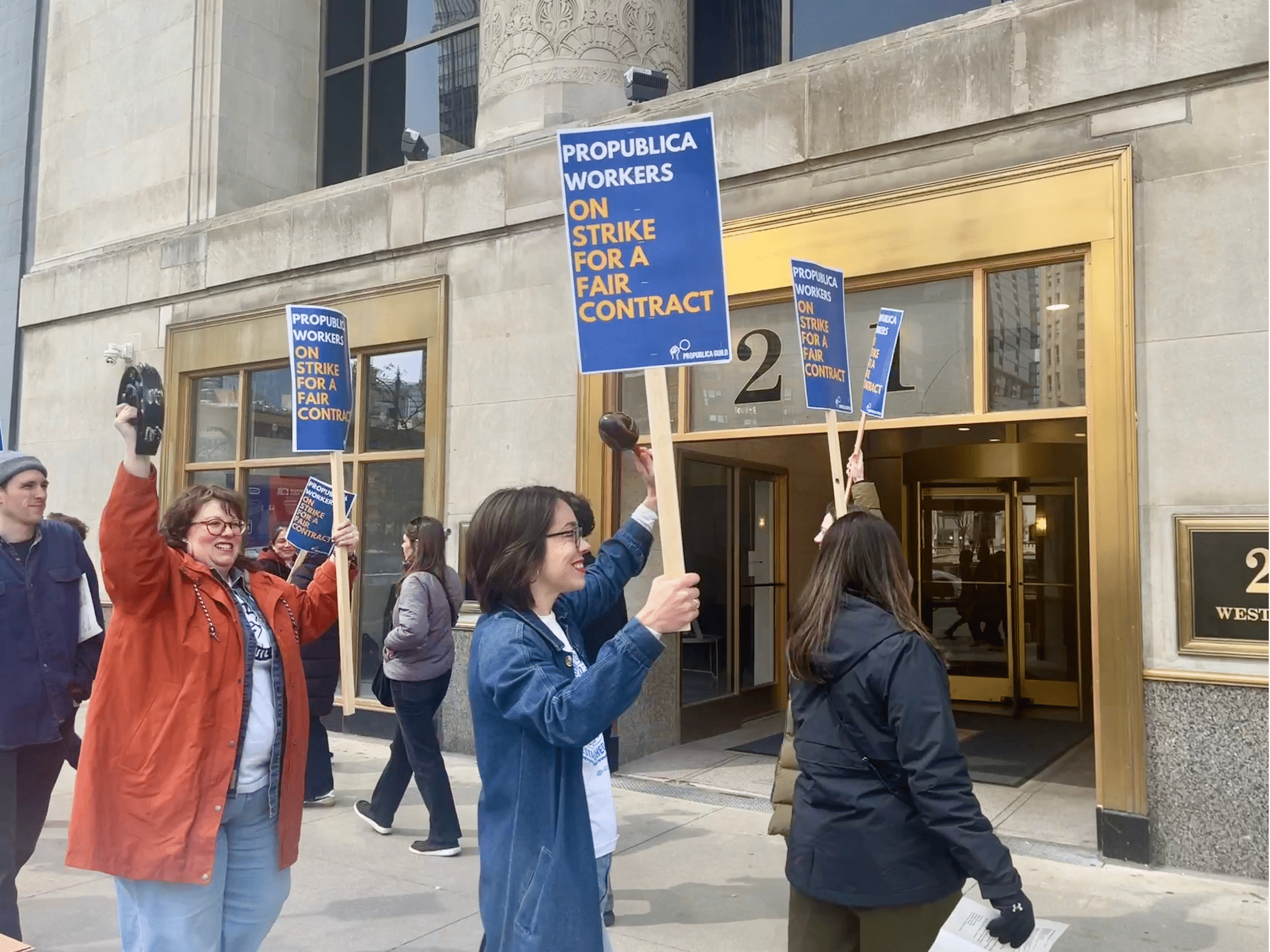 Several workers in a circle picketing the Chicago office of ProPublica hold up signs that say "ProPublica workers on strike for a fair contract."